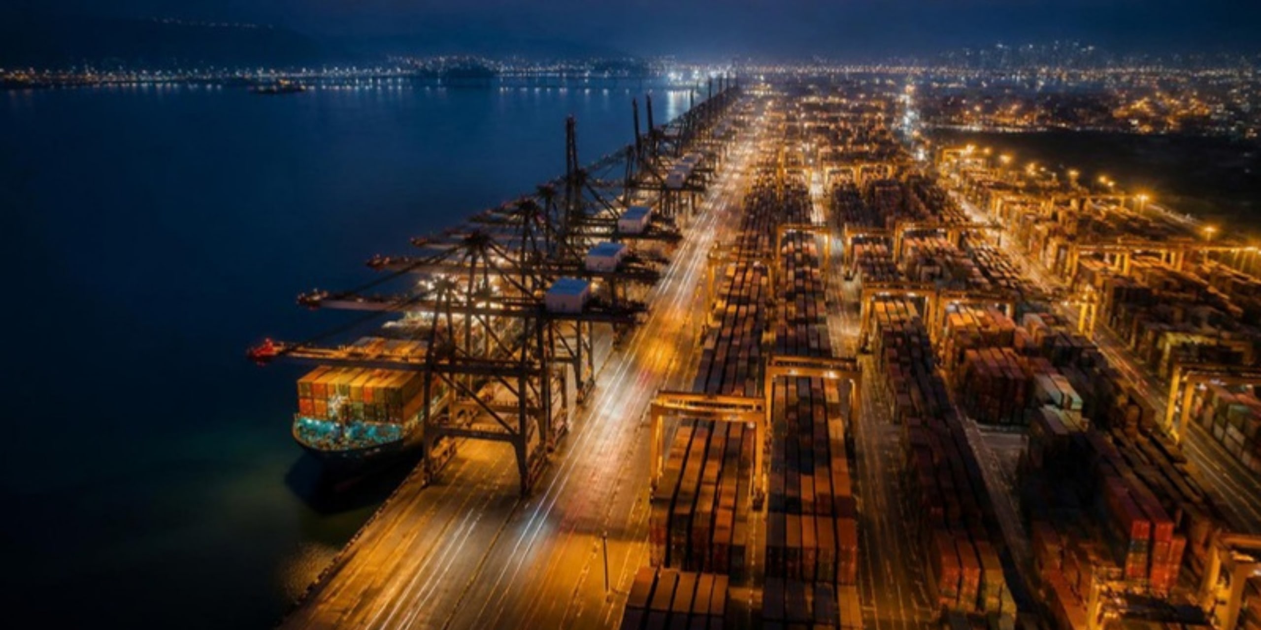 Night aerial view of a container terminal lit by golden lights
